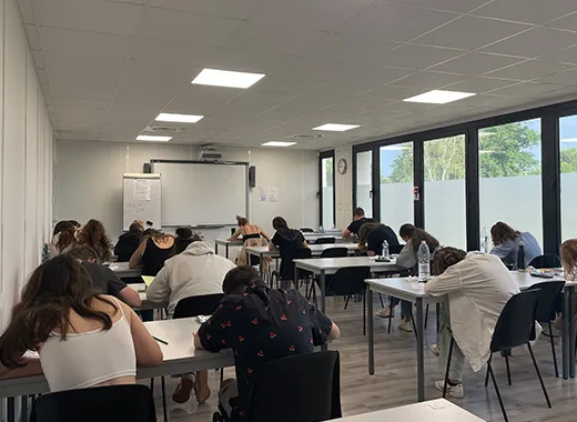 Salle de classe avec de nombreuses tables et étudiants en situation de travail